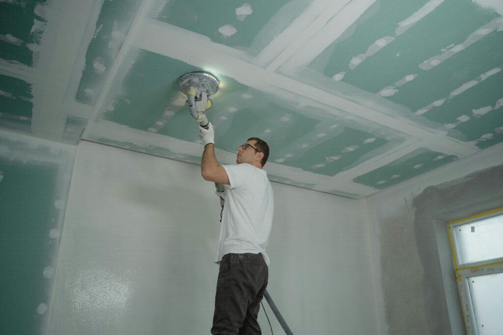 pexels-photo-6474129-6474129 A worker expertly polishes a ceiling indoors, demonstrating home renovation skills.
